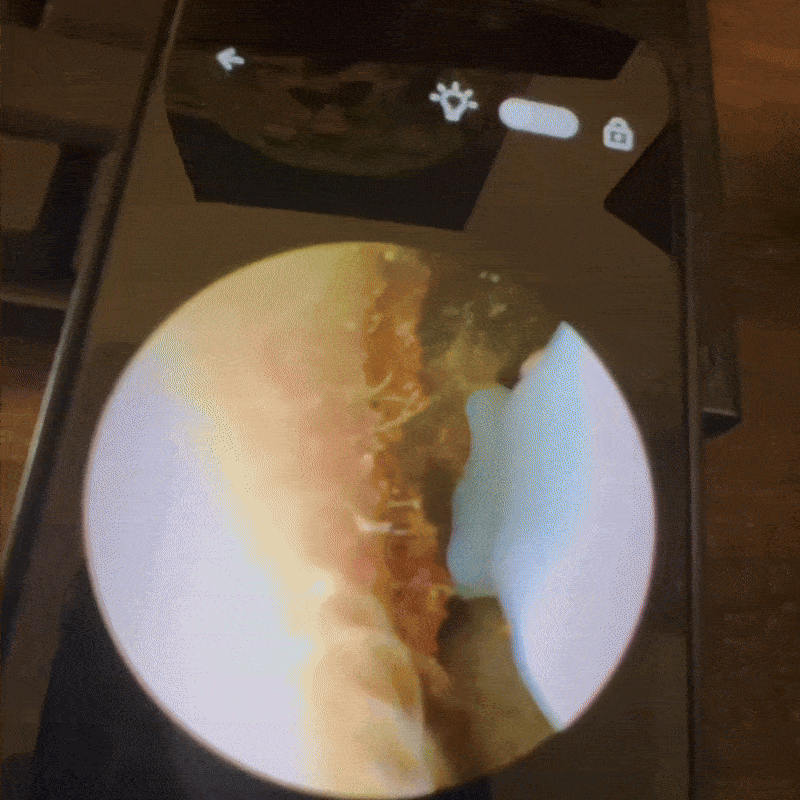 A smartphone screen showing a close-up view through a circular lens.